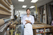 Foto: Portrait of a happy young craftsman standing with arms crossed in workshop Portrait of a happy young craftsman standing with arms crossed in workshop