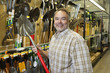 Foto: Portrait of a happy mature man holding shovel in hardware store Portrait of a happy mature man holding shovel in hardware store