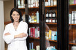 Foto: Portrait of a beauty salon employee standing with arms crossed and cosmetics in background Portrait of a beauty salon employee standing with arms crossed and cosmetics in background