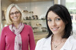 Portrait of a mid adult optician with happy female customer in store
