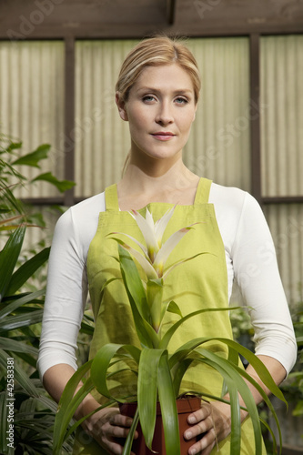 Photo: Portrait of a young woman holding potted plant Portrait of a young woman holding potted plant
