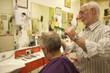 Barber cutting senior man's hair in barbershop