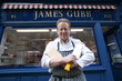 Photo: Portrait of a happy senior butcher standing with crossed cleavers in hands outside shop Portrait of a happy senior butcher standing with crossed cleavers in hands outside shop