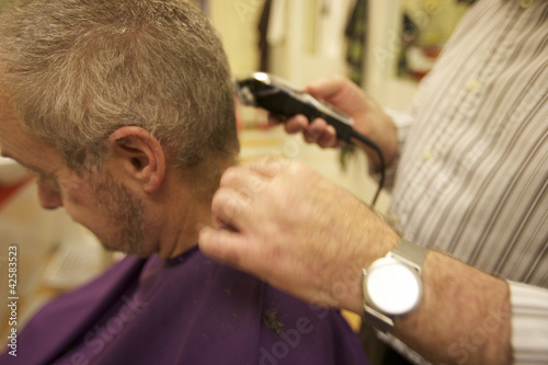 Photo: Midsection of senior barber giving haircut to customer in salon Midsection of senior barber giving haircut to customer in salon