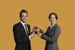 Portrait of happy partners holding winning trophy together