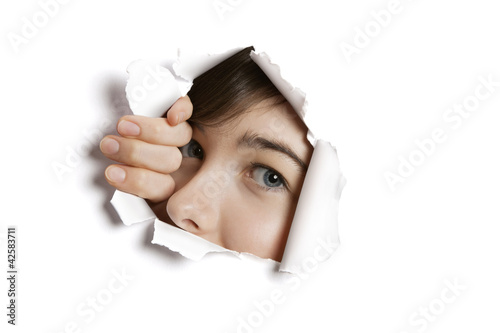 Foto: Portrait of a young Middle eastern woman peeking from ripped white paper hole Portrait of a young Middle eastern woman peeking from ripped white paper hole