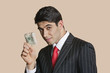 Foto: Portrait of a young businessman showing paper money over colored background Portrait of a young businessman showing paper money over colored background