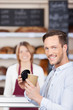 zufriedener kunde mit kaffee in der bäckerei