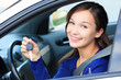Pretty female driver in a white car showing the car key