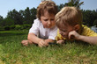 two boys with magnifying glass outdoors
