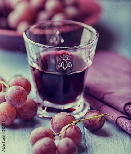 Photo: Glass of red wine and grapes on the table Glass of red wine and grapes on the table