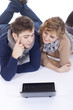 Foto: young couple lying on the floor while using a laptop young couple lying on the floor while using a laptop