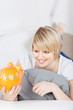 Foto: blonde frau schaut sparschwein an blonde frau schaut sparschwein an