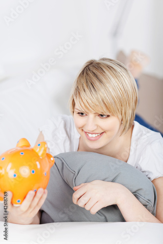 Photo: blonde frau schaut sparschwein an blonde frau schaut sparschwein an