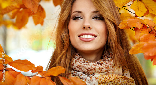 Photo: Beautiful elegant woman standing in a park in autumn Beautiful elegant woman standing in a park in autumn