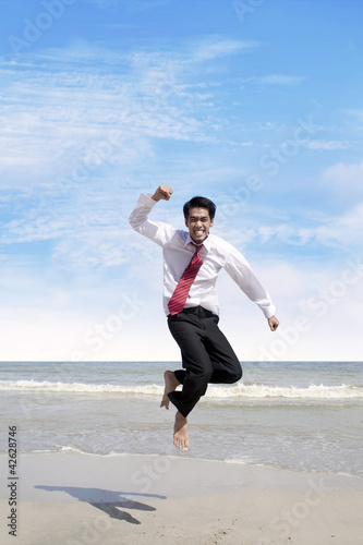 Photo: Success bussinessman jumps at beach Success bussinessman jumps at beach
