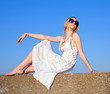 Attractive young woman in white sundress sitting outdoors