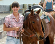 A smiling woman takes a break during a horse event.