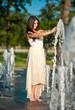 young beautiful  brunette girl playing at outdoor water fountain