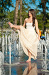 young beautiful  brunette girl playing at outdoor water fountain