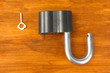 old padlock with key on wooden background close-up