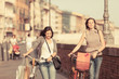 Two Beautiful Women Walking in the City with Bicycles and Bags