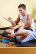 Frau neben Trainer im Fitnesscenter
