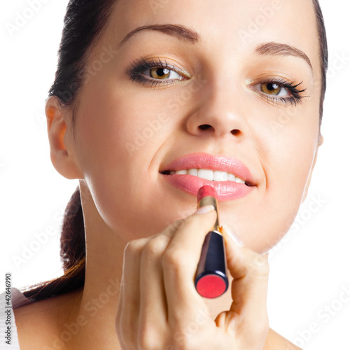 Foto: Woman applying lipstick, isolated Woman applying lipstick, isolated