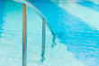 Swimming pool Stairs with hand-rails on water background.