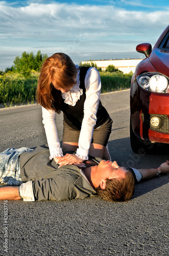 Photo: Young man reanimation on a road. Concept first aid Young man reanimation on a road. Concept first aid