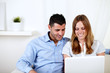 Foto: Young couple smiling and using a laptop Young couple smiling and using a laptop