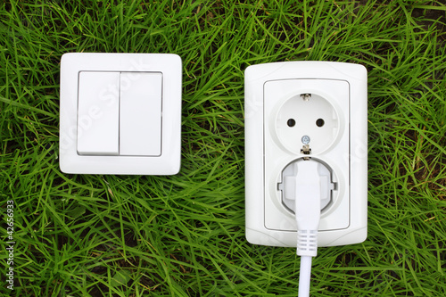 Photo: power receptacle and light switch on a green grass power receptacle and light switch on a green grass