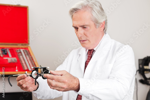 Photo: Optometrist Examining Trial Frame For Eye Test Optometrist Examining Trial Frame For Eye Test
