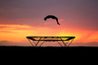 silhouette of gymnast on trampoline in sunset