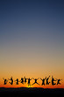 silhouette of teenagers jumping in sunset for fun