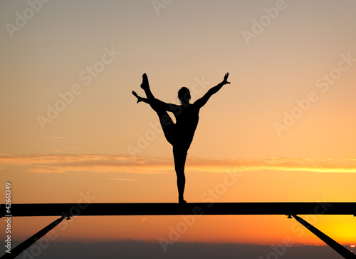 Photo: silhouette of female gymnast on balance beam in sunset silhouette of female gymnast on balance beam in sunset