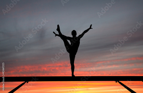 Photo: silhouette of female gymnast on balance beam in sunset silhouette of female gymnast on balance beam in sunset