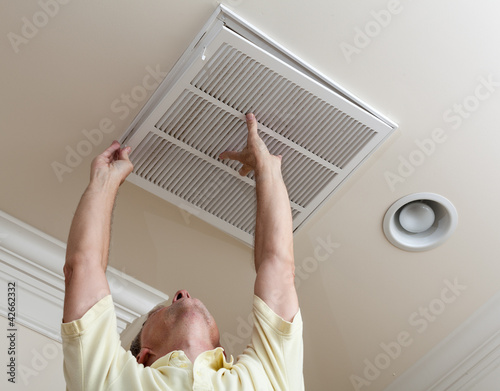Photo: Senior man opening air conditioning filter in ceiling Senior man opening air conditioning filter in ceiling