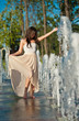 young beautiful brunette girl playing at outdoor water fountain