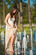 young beautiful brunette girl playing at outdoor water fountain