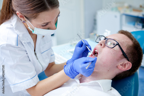 Photo: dentist at work on woman patient in office dentist at work on woman patient in office