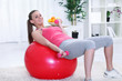 Woman doing fitness exercise with dumbbells on fit ball