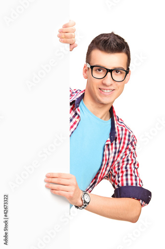 Photo: A smiling handsome male posing behind a white panel A smiling handsome male posing behind a white panel