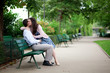 Romantic couple on a bench, girl is whispering something to her