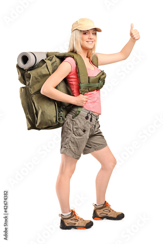 Foto: Full length portrait of a female hiker with backpack giving a th Full length portrait of a female hiker with backpack giving a th