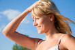 young blond girl in a bikini sunbathing against blue sky