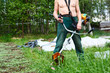 Unrecognizable man a lawn-mower with weed trimer on lawn