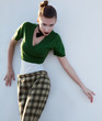Pretty girl standing in checked pants over white wall