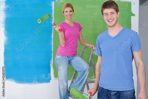 Photo: happy couple paint wall at new home happy couple paint wall at new home