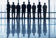 Photo: Silhouette of business people in a row looking out lobby window Silhouette of business people in a row looking out lobby window